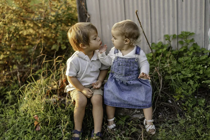 Deux jeunes enfants partageant un moment complice en extérieur.